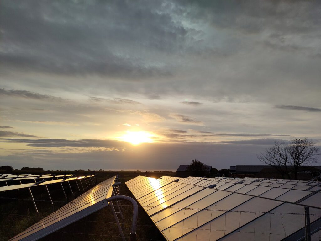 Sonne geht hinter Wolken über Solarthermieanlage unter.